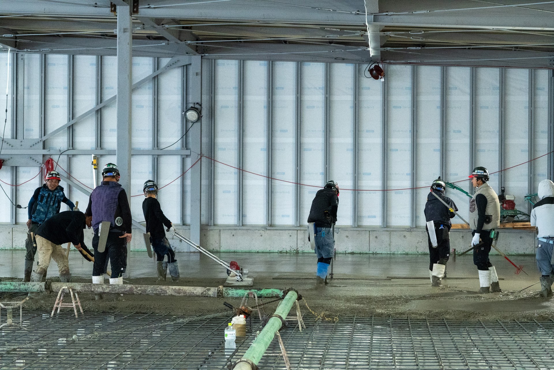 大規模現場で土間コンクリートの打設・均し作業を行う株式会社渡邉工業の職人たち