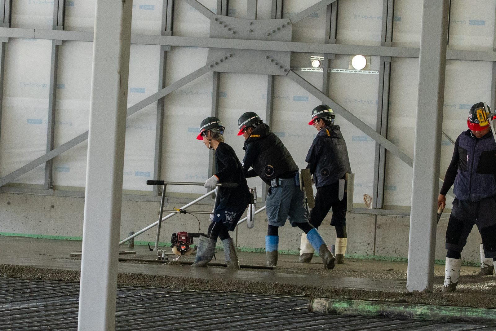 隊列を組んで現場を進む4名の職人チーム